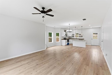Unfurnished living room featuring a chandelier, light wood-style floors, a ceiling fan, and recessed lighting