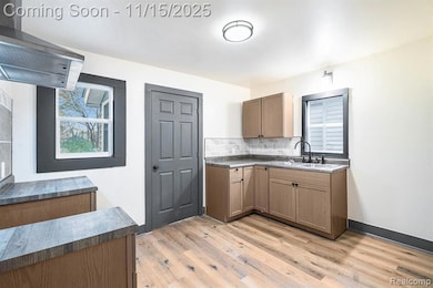 Kitchen featuring extractor fan, light wood-style floors, and decorative backsplash