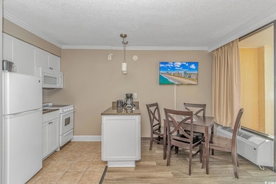 Kitchen with white cabinets, white appliances, a textured ceiling, crown molding, and hanging light fixtures