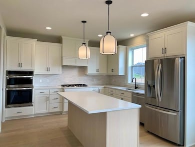 Large gourmet kitchen features custom cabinets, gas cooktop, vented hood, quartz countertops, and ceramic tile backsplash.