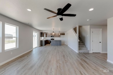Unfurnished living room featuring stairway, light wood-type flooring, a ceiling fan, and recessed lighting