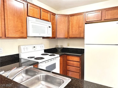 Kitchen featuring brown cabinets, white appliances