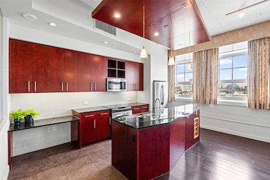 Kitchen with dark countertops, reddish brown cabinets, tasteful backsplash, appliances with stainless steel finishes, and recessed lighting