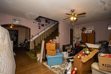Living room with wood finished floors, a textured ceiling, stairway, and ceiling fan