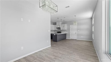 Unfurnished living room with a chandelier and light wood-type flooring