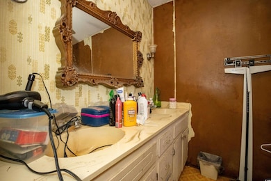 Bathroom with wallpapered walls, a sink, and double vanity