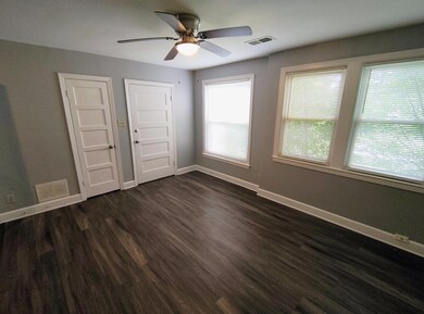 Empty room with ceiling fan and dark wood finished floors