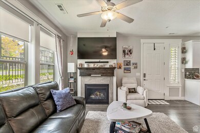 Living room with wood finished floors, a tile fireplace, and ceiling fan