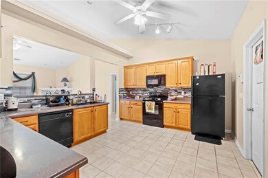 Kitchen featuring lofted ceiling, a ceiling fan, decorative backsplash, black appliances, and light tile patterned flooring