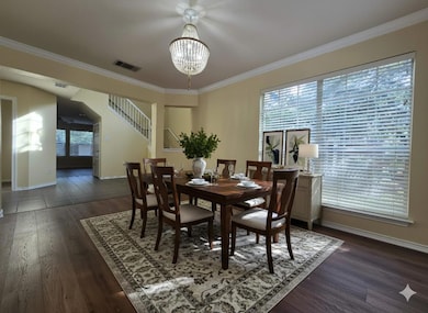 Dining space with crown molding, dark wood-style floors, stairway, and a chandelier