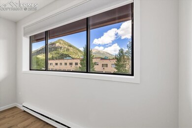 Unfurnished room with baseboard heating, wood finished floors, and a mountain view
