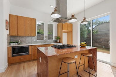 Kitchen with black appliances, light wood finishe