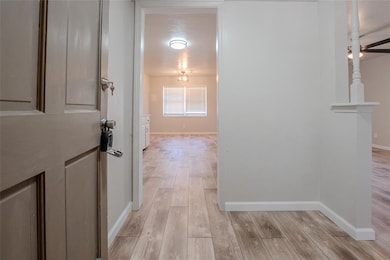 Corridor featuring light wood finished floors and baseboards