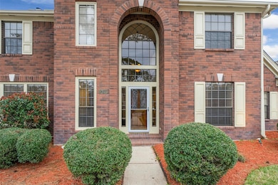 Mature landscaping frames the walkway. The covered entryway features brick lined steps and an updated storm door.