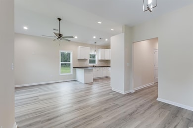 Unfurnished living room with a ceiling fan, light wood-style flooring, a sink, recessed lighting, and baseboards