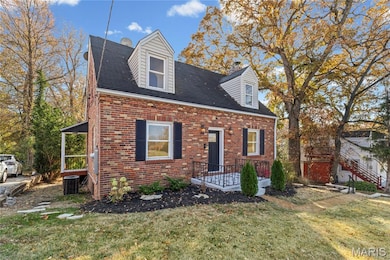 Cape cod home with a front yard, roof with shingles, and brick siding