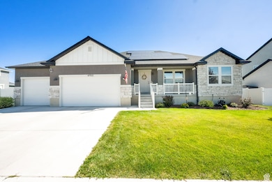 View of front facade with stone siding, board and batten siding, a porch, and a garage