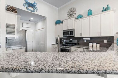 Kitchen featuring stainless steel appliances, crown molding, decorative backsplash, stone countertops, and recessed lighting