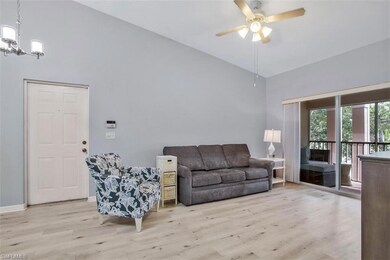 Living room featuring high vaulted ceiling, light hardwood / wood-style flooring, and ceiling fan with notable chandelier