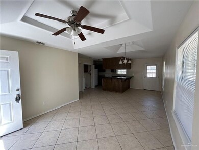 Unfurnished living room featuring a raised ceiling, light tile patterned floors, baseboards, and ceiling fan
