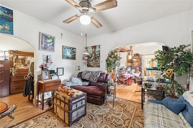Living area featuring arched walkways, wood finished floors, and a ceiling fan