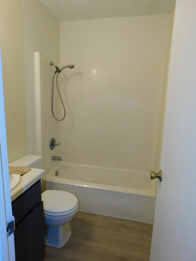 Bathroom with dark wood-type flooring, vanity, and bathtub / shower combination