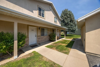 Property entrance with stucco siding, brick siding, covered porch, and a yard