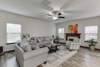 Living area featuring wood finished floors, healthy amount of natural light, ceiling fan, and baseboards