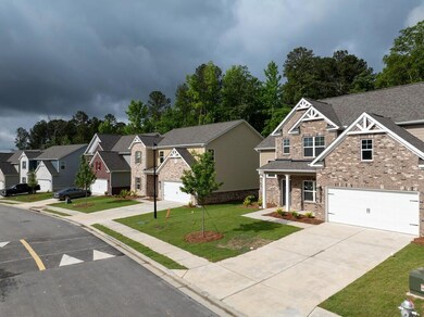 View of front facade with brick siding, driveway, roof with shingles, a residential view, and a front yard