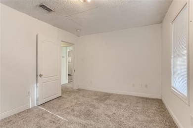 Unfurnished room with light carpet, a textured ce