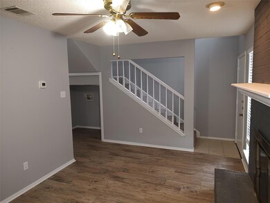 Foyer entrance with wood finished floors, a ceiling fan, stairs, and a textured ceiling