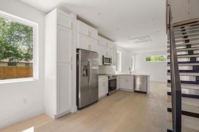 Kitchen with a sink, light wood-type flooring, a peninsula, white cabinetry, and stainless steel appliances
