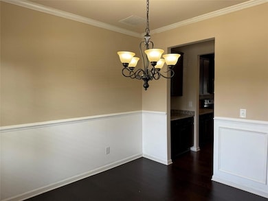 Unfurnished dining area featuring dark wood-type flooring, a chandelier, and ornamental molding