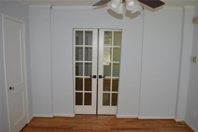 Unfurnished room featuring a ceiling fan, ornamental molding, french doors, and wood finished floors