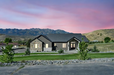View of front facade with a mountain view, board and batten siding, stone siding, and a front lawn