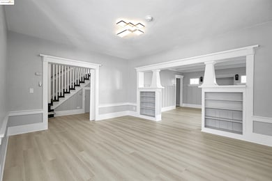 Unfurnished living room featuring wood finished floors and stairs