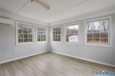 Empty room featuring light wood-type flooring, an AC wall unit, and wood walls