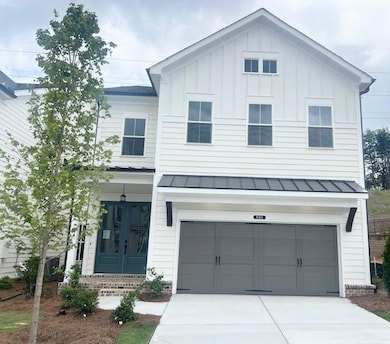 View of front of house featuring a standing seam roof, a garage, board and batten siding, driveway, and a metal roof