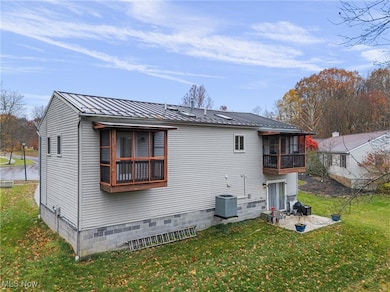 Rear view of property featuring a yard, a metal roof, a standing seam roof, and crawl space