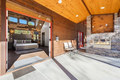 Bedroom featuring wood walls, a stone fireplace, wood ceiling, and high vaulted ceiling