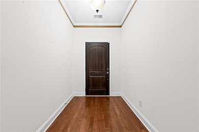 Doorway to outside with crown molding and wood finished floors