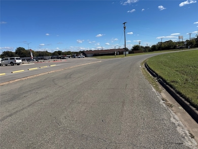 View of asphalt road featuring curbs and street lighting