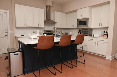 Kitchen featuring wall chimney exhaust hood, ligh