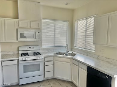 Kitchen featuring white appliances, white cabinets, light countertops, and light tile patterned floors