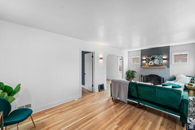 Living room featuring light wood-type flooring, arched walkways, and a brick fireplace