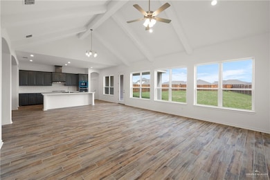 Unfurnished living room with beamed ceiling, ceiling fan, light wood-type flooring, arched walkways, and recessed lighting