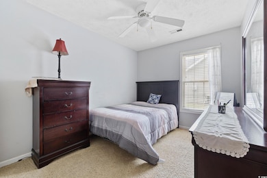 Bedroom featuring light carpet, a textured ceiling, and a ceiling fan