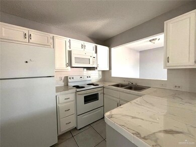 Kitchen featuring tasteful backsplash, white appliances, white cabinetry, and a sink
