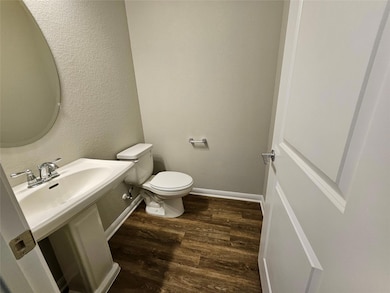 Bathroom with wood finished floors, toilet, baseb