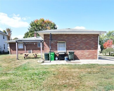Rear view of property featuring brick siding, a lawn, and a patio